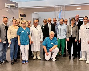 Gruppe von medizinischem Personal und Fachleuten in Arbeitskleidung, versammelt in einem modernen Gesundheitsumfeld.